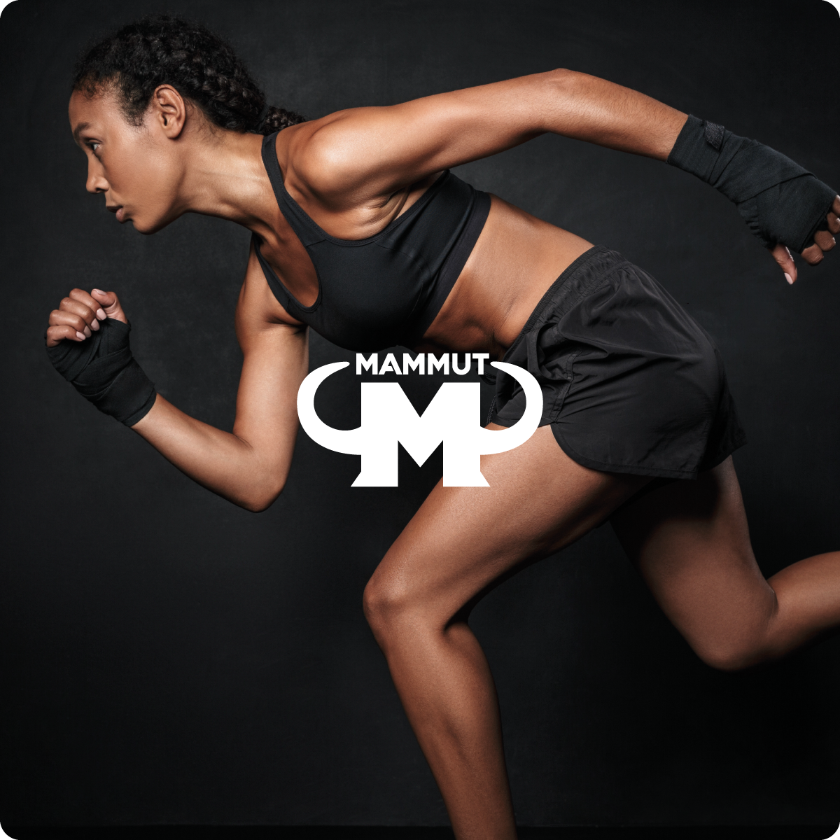 Sportliche Frau in schwarzer Trainingskleidung läuft in athletischer Pose vor dunklem Hintergrund, darüber das weiße Mammut Nutrition Logo.