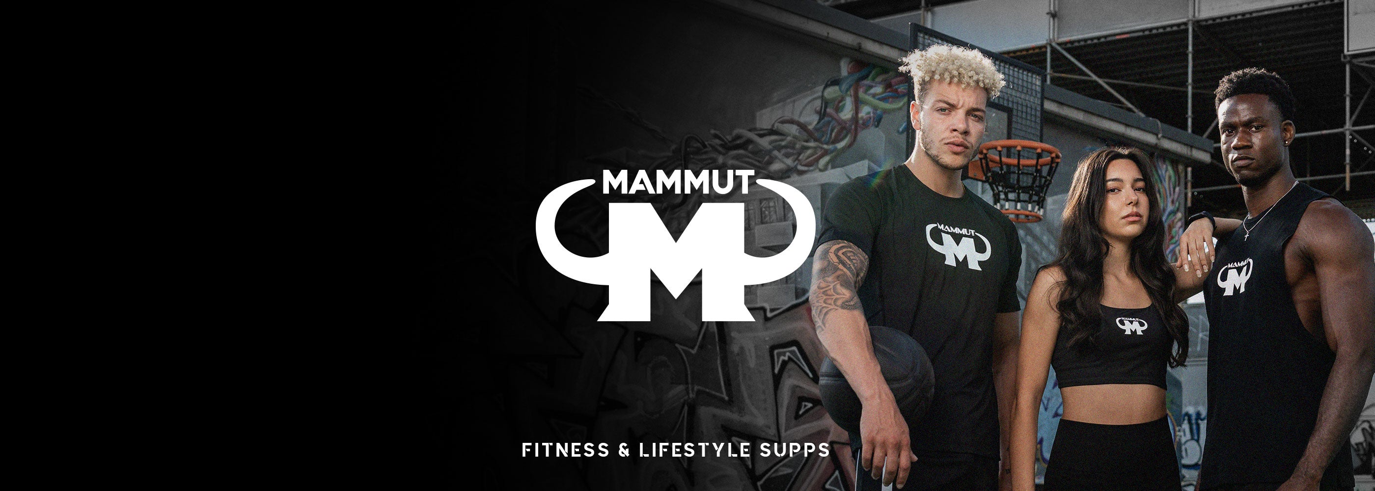 Drei junge Sportler in schwarzer Mammut Nutrition Kleidung posieren ernst vor Graffiti-Wänden auf einem Basketballplatz, mittig das Mammut Logo mit dem Schriftzug ‚Fitness & Lifestyle Supps‘.
